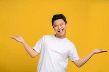 Asian man wearing a white T-shirt was excited for something on a yellow studio background with copy space.