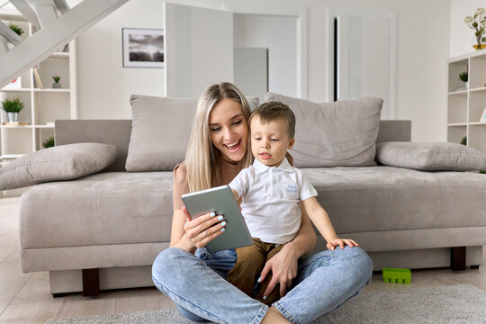 Happy Family Mom Teaching Cute Child Son Holding Digital Tablet At Home. Young Mother And Toddler Kid Boy Using Pad Computer For Playing, Learning, Watching Funny Videos Or Video Call Virtual Meeting.