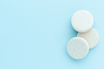 Heap of medicine pills on blue surface, isolated, top view. Circle round medical tablets, paracetamol or analgesic medication.