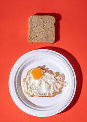 fried egg on paper plate with toast bread on red background. stock photo
