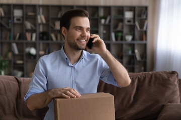 Happy millennial Caucasian male client or buyer receive post parcel shopping online talk on...