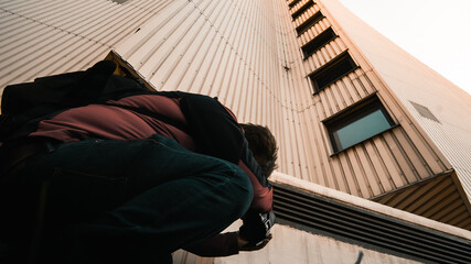 A man taking a picture of a house. He is crouching to get a low angle with his camera.