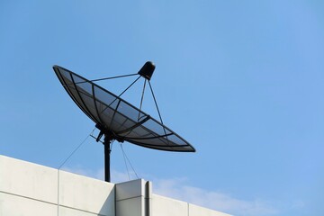 Satellite dish on roof top of building with blue sky background. Technology and object concept.