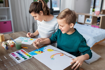 family, leisure and people concept - mother and little son with colors and paper drawing at home