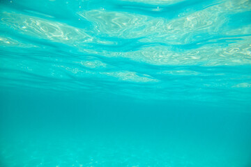 Turquoise calm sea with waves and rays of sunlight shining through, underwater. Ocean. Tranquility and silence. Beautiful natural background, wallpaper