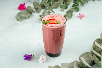Glass of strawberry smoothie cocktail on the blue background
