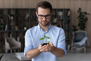 Happy young Caucasian businessman hold soil green plant think plan business project launch....