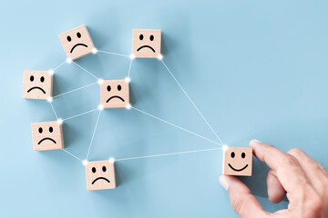 Close up top view customer hand choose smiley face on wood cube, Service rating, satisfaction...