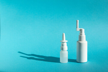 Nasal spray and throat spray on a blue background, place for text. Treatment of viral and cold diseases, new drugs for COVID-19.