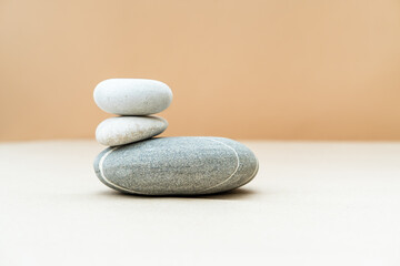 Pile of gray stones on beige background. Simple balancing stones, simplicity of harmony and balance. Place for text.