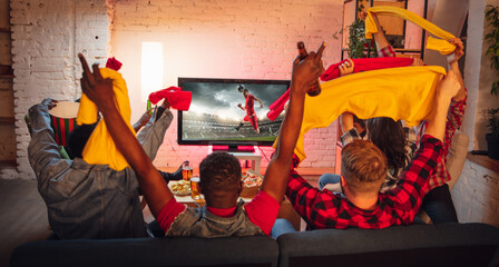 Group of friends watching TV, sport match together. Emotional fans cheering for favourite team, watching on exciting game. Concept of friendship, leisure activity, emotions