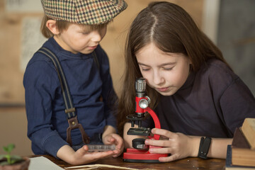 a boy and a girl, brother and sister, look through a microscope, do an experiment, a biology or botany lesson