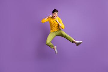 Fototapeta na wymiar Full size photo of young crazy positive funky funny man doing karate in air jumping isolated on purple color background