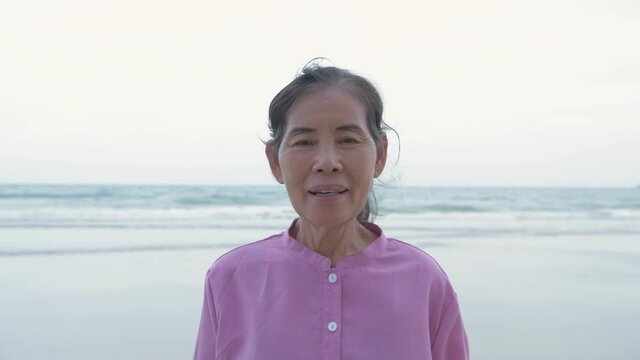 Travel concept of 4k Resolution. Asian old woman introducing beachside attractions.