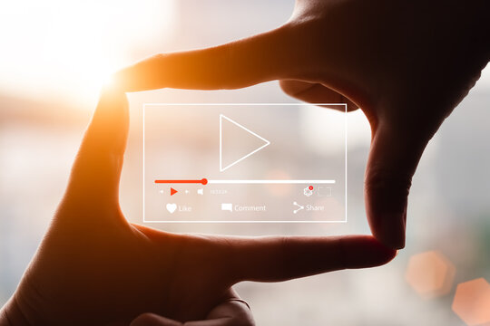 Concept of watching live video online, hands making framing view on blurred sunset background.