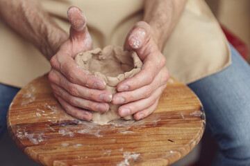The master creates a white clay product. The master's hands clos