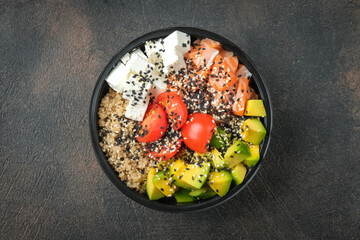 Poke bowl with quinoa, salmon, avocado and feta cheese on a dark background top view. Home delivery food.