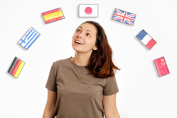 The concept of learning foreign languages. Portrait of young smiling woman looks at the flags of...