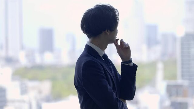 窓の外を見て考え事をするビジネスマン