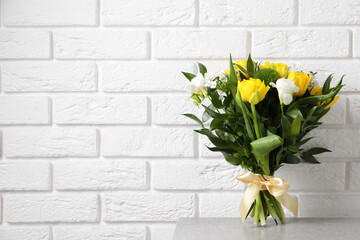 Beautiful bouquet with peony tulips on light table near white brick wall. Space for text
