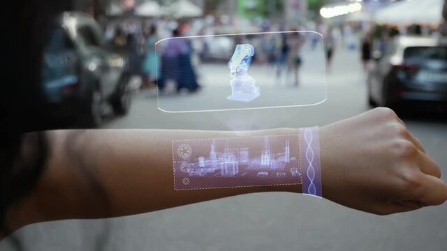 Female hand activates conceptual HUD holograms on smart bracelet with Automatic industrial robo hand. Unrecognizable woman with holographic technology on a city street background