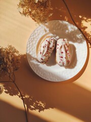 Delightful eclairs with white glaze and raspberry crumb. Concept baking, cookbook recipes, bakery banner, cafe advertisement.