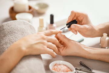 Woman applying nail polish at nail salon