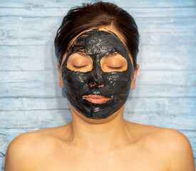 Woman relaxing with black charcoal facial mask