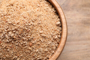 Fresh breadcrumbs in bowl on wooden table, top view