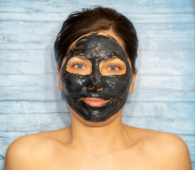 Woman relaxing with black charcoal facial mask