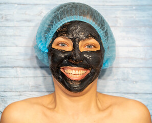 Woman relaxing with black charcoal facial mask