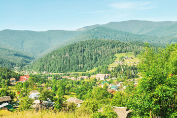Summer landscape with village in valley and mountain in distance by blue sky in Carpathians, Ukraine