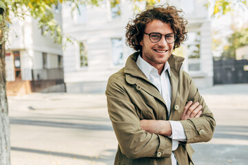 A young successful businessman in eyewear smiling broadly posing outdoors. Male entrepreneur...