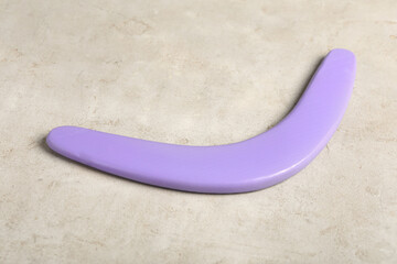 Purple boomerang on light grey background. Outdoors activity