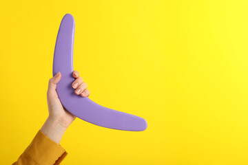 Woman holding boomerang on yellow background, closeup. Space for text