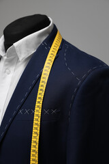Semi-ready jacket with tailor's measuring tape on mannequin, closeup