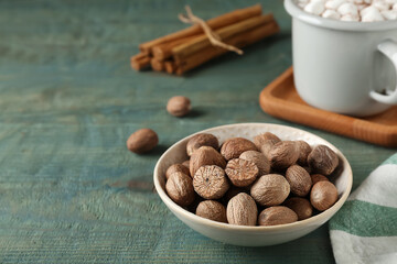 Nutmegs in bowl on blue wooden table. Space for text
