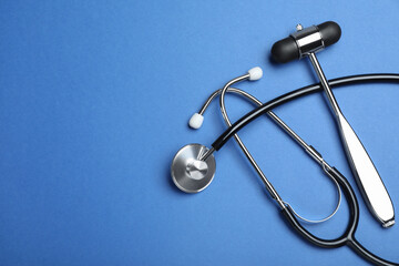 Reflex hammer, stethoscope and space for text on blue background, flat lay. Nervous system diagnostic