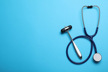 Reflex hammer, stethoscope and space for text on light blue background, flat lay. Nervous system diagnostic