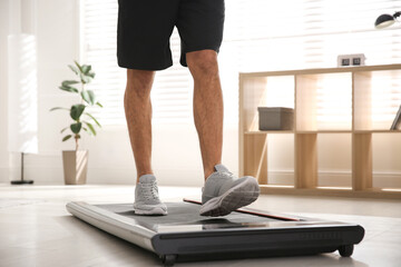 Sporty man training on walking treadmill at home, closeup © New Africa