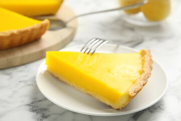 Slice of delicious homemade lemon pie on white marble table