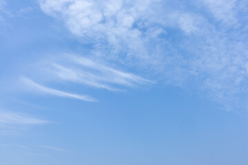 Blue sky with fluffly white scattered clouds day time landscape background.