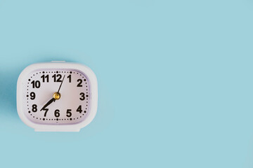 Alarm clock on a blue background. Top view of a white clock. The symbol of early rise to work, to school.