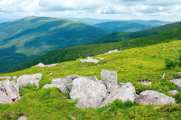 Fototapeta na wymiar stones on the hill of mountain meadow. beautiful summer landscape with clouds above the horizon