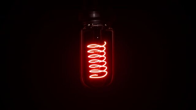 Switching on, turning off light bulb animation. Red light over dark black background. Bright glowing and flickering Edison, Tungsten lamp. Retro vintage lamp shape or form. 3D Render 4K animation