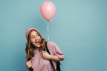 Young excited student girl laughing and posing with balloon