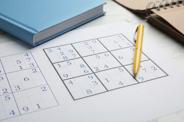 Sudoku, pen and planner on white table, closeup