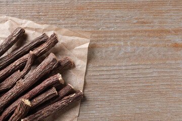 Dried sticks of liquorice root on wooden table, top view. Space for text