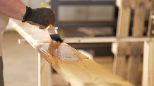 Carpenter applying colorless protective coat on Termo pine material. Lasur to enhance natural wood texture.