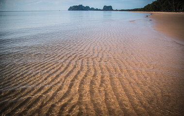 The waves of the sea when hitting the morning light create light trails on the beach.
